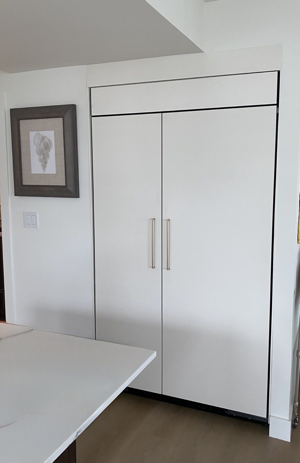 Finished panel-ready built-in refrigerator integrated with white kitchen cabinetry
